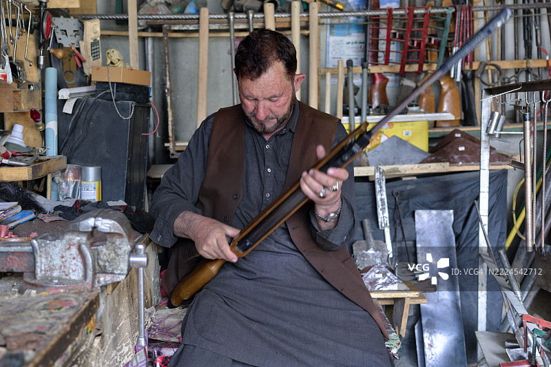 在巴基斯坦的工作坊中，枪匠正在仔细组装步枪。图片素材