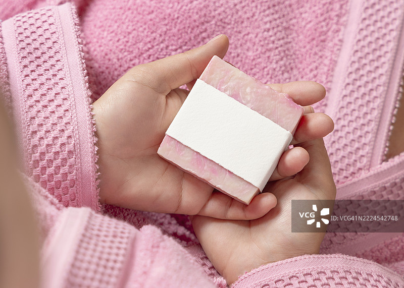 年轻女性穿着粉色浴袍，手中拿着一块没有标签的香皂，特写，布林迪西，普利亚，意大利图片素材