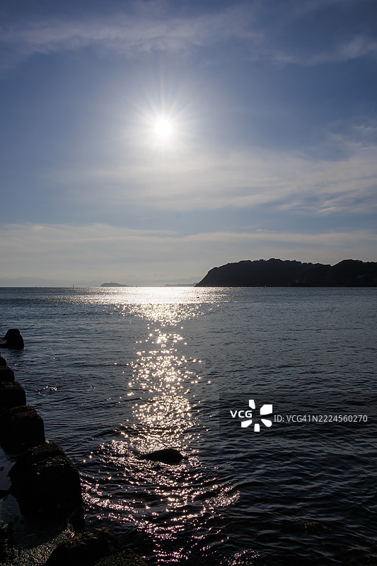 逗子海滩挤满了来自海外的游客。地平线上是江之岛和山的轮廓。这里也是风帆冲浪和立式划水的圣地。一些人在防波堤上钓鱼。图片素材