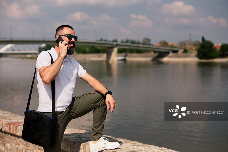 一位英俊的中年男子留着胡须，正在打电话。图片素材
