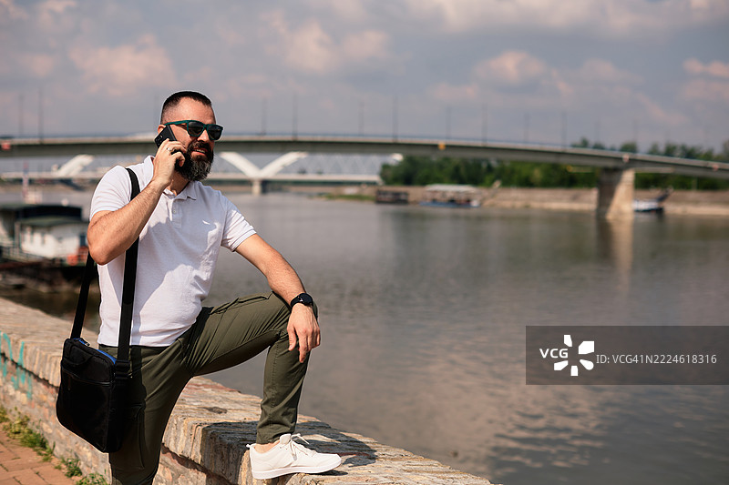 一位英俊的中年男子留着胡须，正在打电话。图片素材