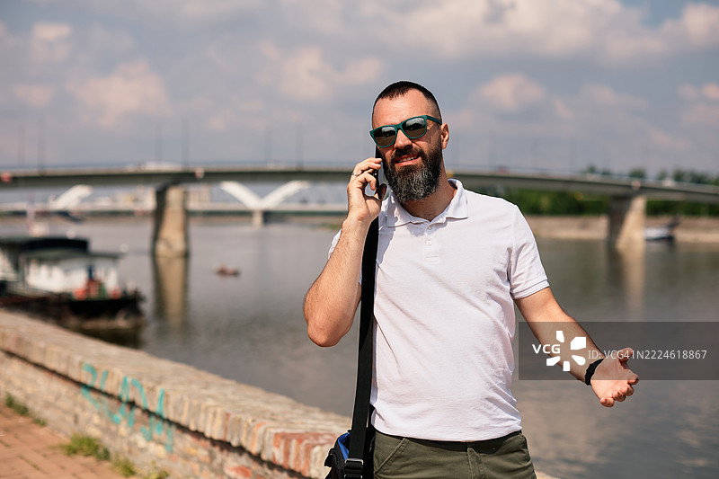 一位英俊的中年男子留着胡须，正在打电话。图片素材