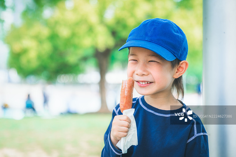 可爱的男孩吃香肠的肖像。图片素材