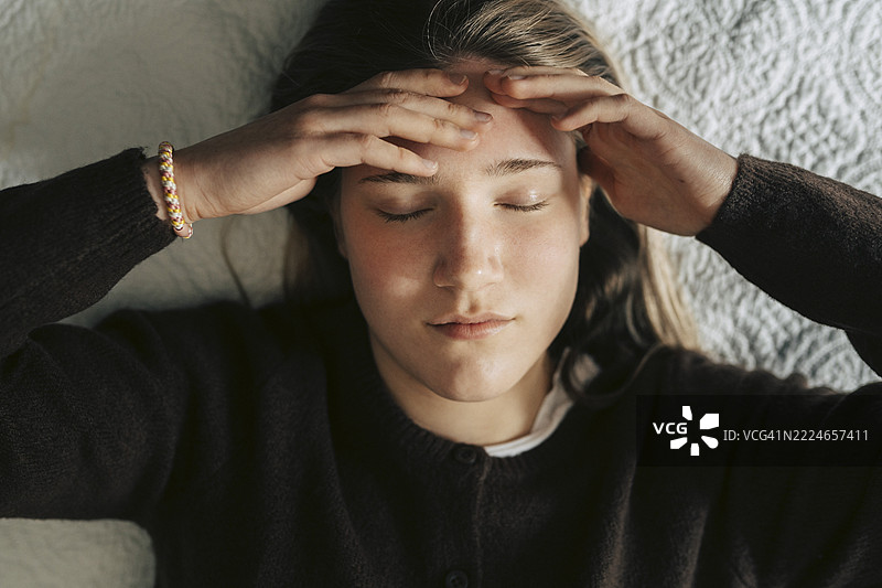 从上方直接拍摄的感到压力的年轻女性躺在床上图片素材
