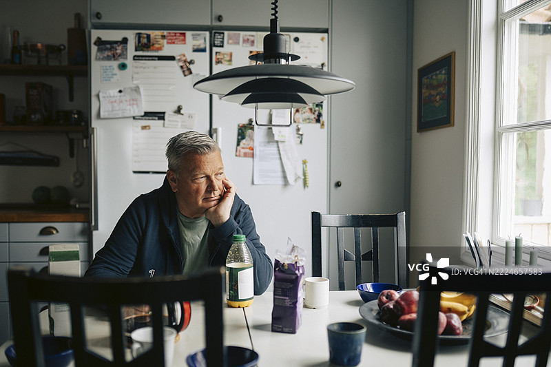 孤独的老年男子在家中的餐桌上吃早餐图片素材