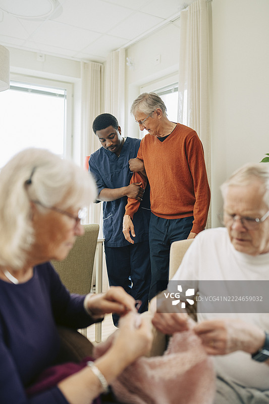 男性护理人员与退休院的老年人手挽手散步图片素材