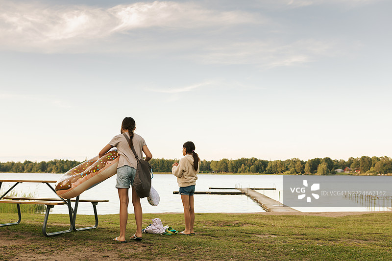 两个孩子在夏天的傍晚前往湖边游泳。图片素材
