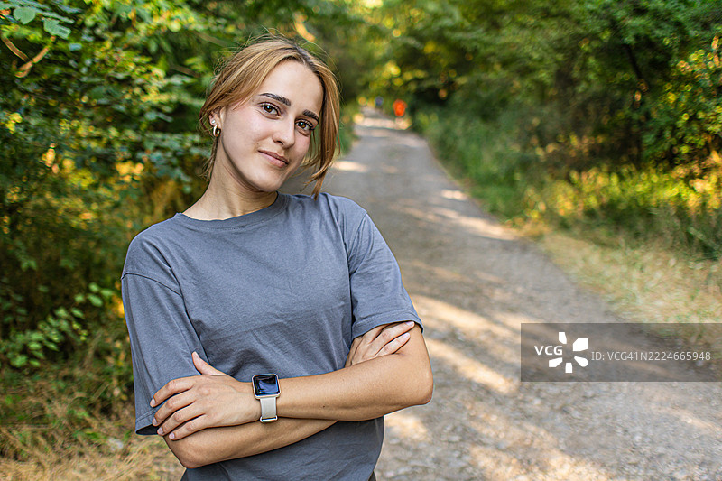 年轻运动员在自然中锻炼后微笑的肖像。她正在享受训练后的休息时光。健康、积极的生活方式在城市公园中。图片素材