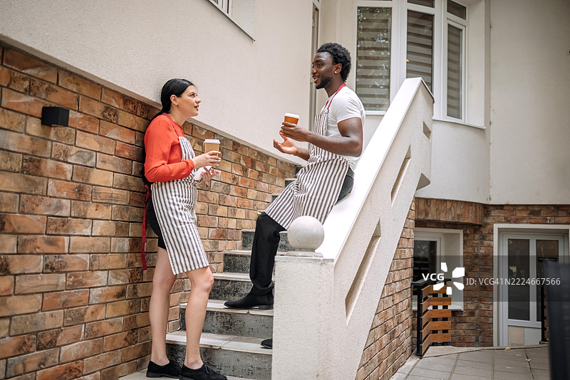 同事们在咖啡馆的楼梯上一起休息，享受咖啡时光。图片素材