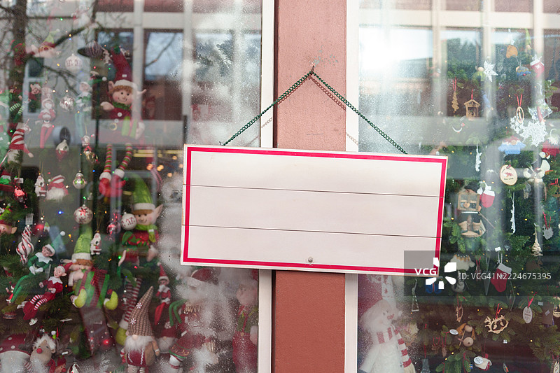 圣诞节空白标签横幅模型悬挂在店面上，用于商店品牌和标志展示。图片素材