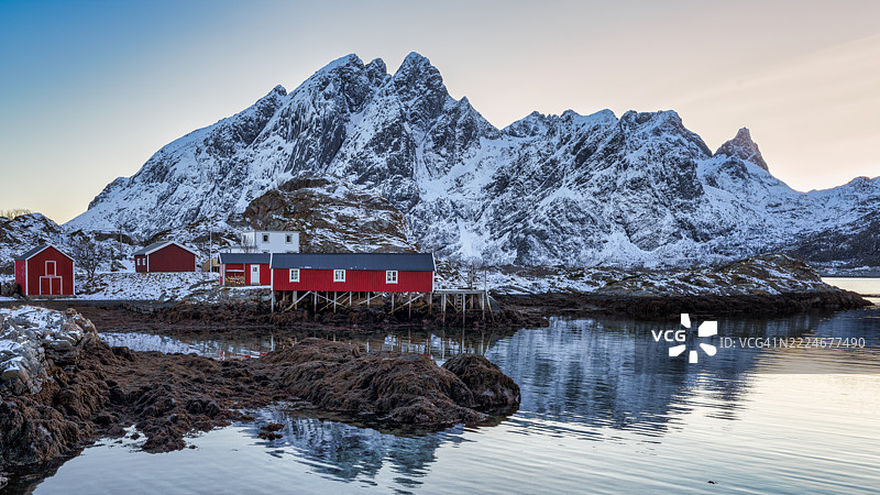 挪威北部洛弗敦群岛的桑德(Sund或Sund i Lofoten)冬季,海湾边的传统红色木制渔民小屋(Rorbuer)与雪山背景相映成趣。图片素材