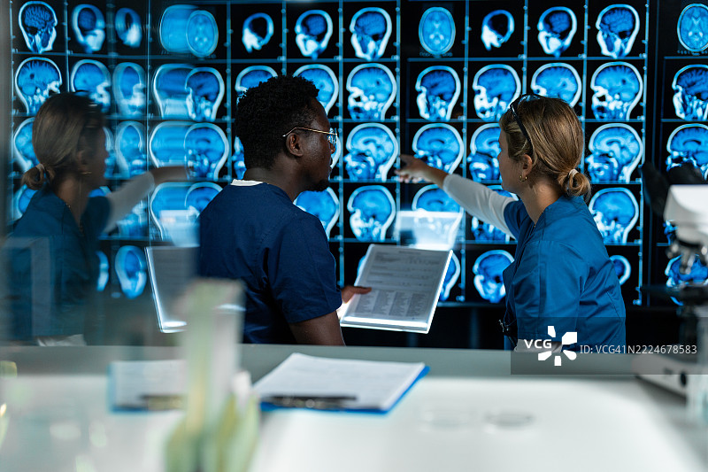 一男一女在实验室讨论MRI脑部扫描的结果。图片素材