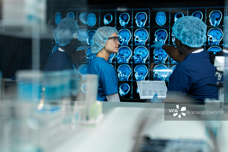 一男一女在实验室讨论MRI脑部扫描的结果。图片素材