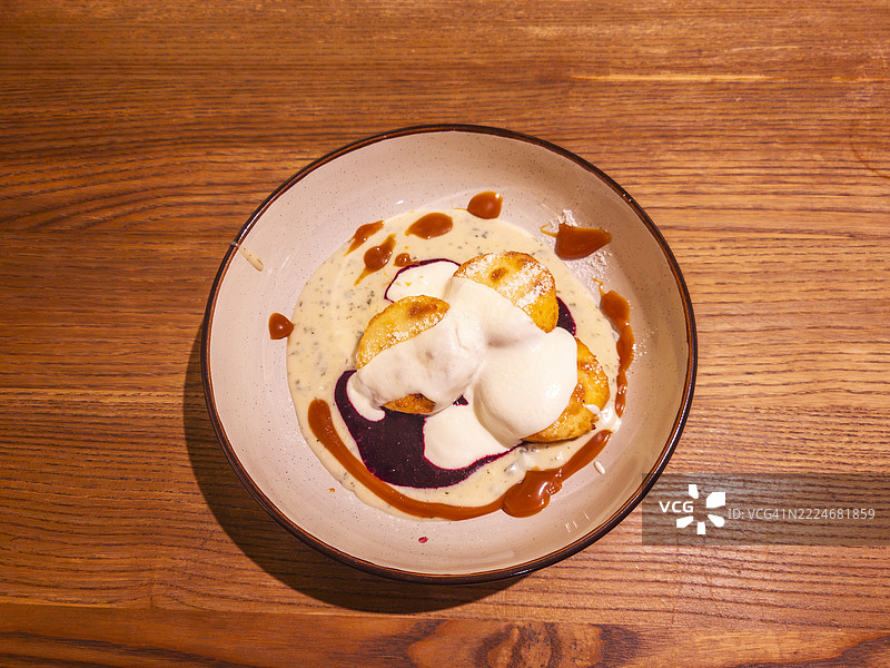 土豆饺子配奶油酱和浆果酱，摆放在木桌上图片素材