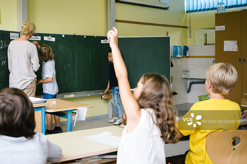 小学教室里的课堂，女老师在讲解，孩子们积极参与。图片素材
