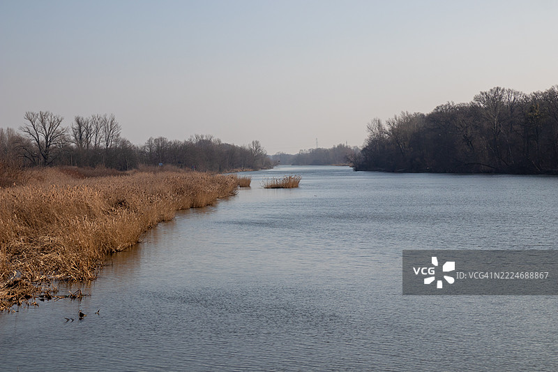 奥德河流经城市风景，绿意盎然的河岸环绕，展现了自然与城市生活的和谐融合，水面上倒映着宁静的景象，波兰图片素材