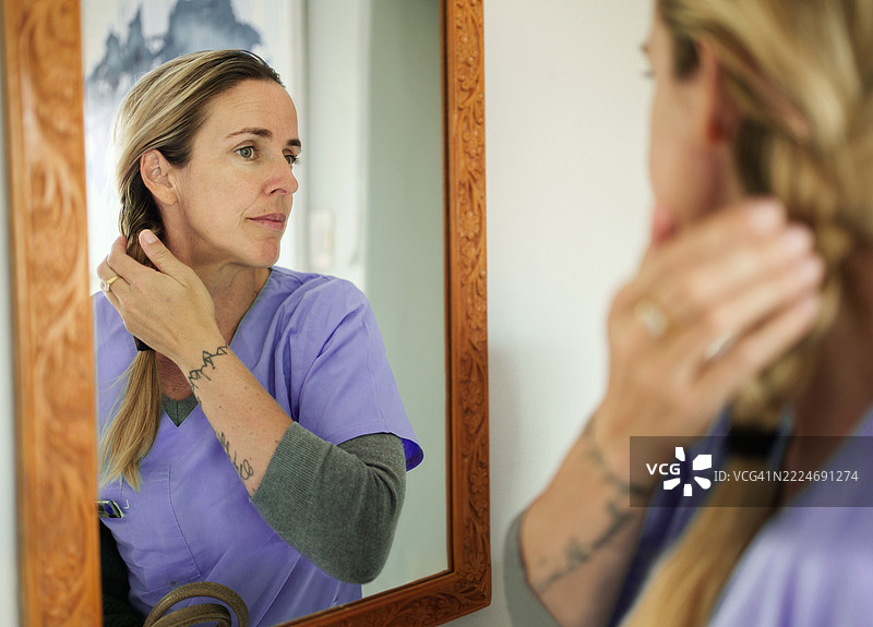 穿着制服的护士在回家后照镜子反思图片素材