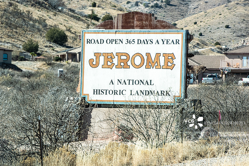 横向全彩特写图像，展示了一个杰罗姆路标，背景是美丽的西南沙漠山脉景色，阳光明媚的日子。图片素材