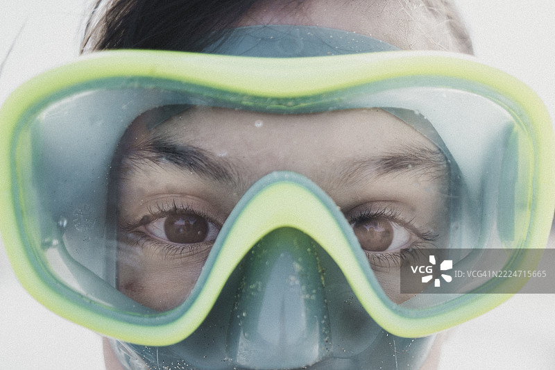 年轻女性调整潜水面罩，满怀期待和兴奋准备进行海洋探索图片素材