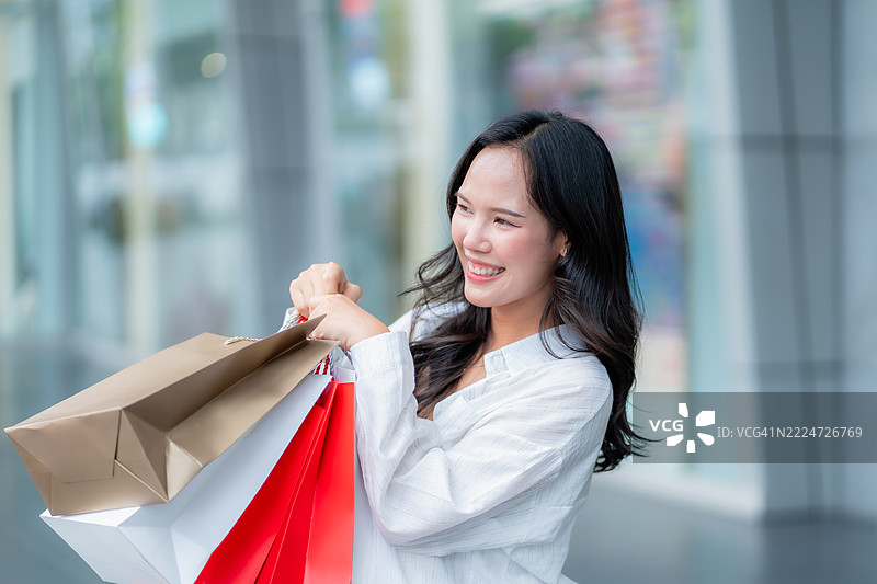 快乐的亚洲女性在户外提着购物袋图片素材