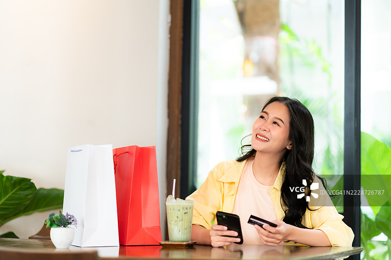 快乐的亚洲女性正在使用信用卡在线购物图片素材
