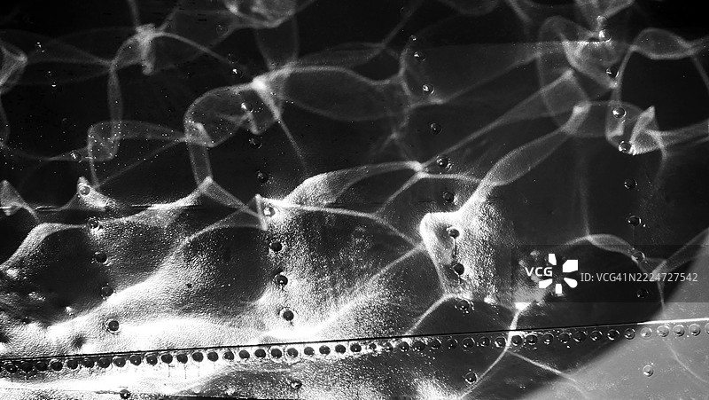 特写镜头，一艘铆接金属船的船体，莱芒湖的水和阳光在其上反射。瑞士洛桑。黑白。图片素材