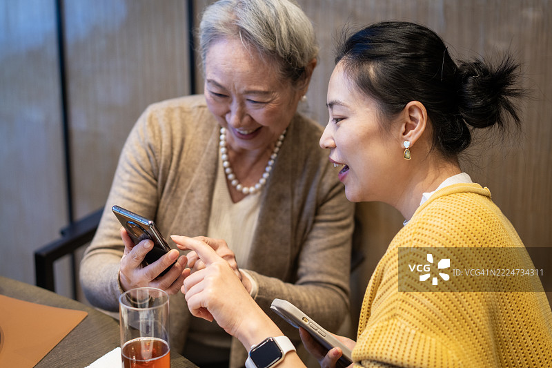 一位老年人与一位年轻女性在餐厅里。图片素材