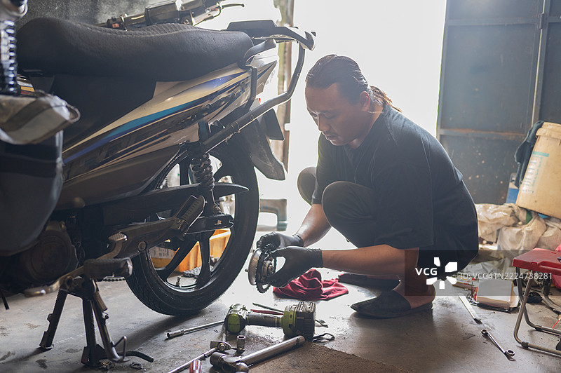在家车库修理摩托车的马来西亚男性机械师图片素材