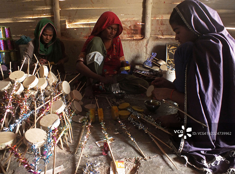 一个巴基斯坦印度教家庭忙于制作玩具和其他游戏材料。图片素材