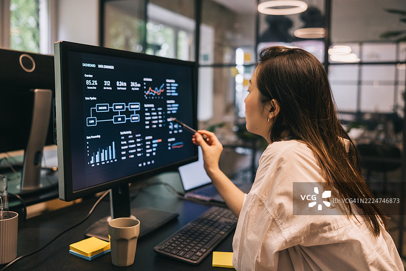 女性分析师在现代办公室环境中查看屏幕上的数据图片素材