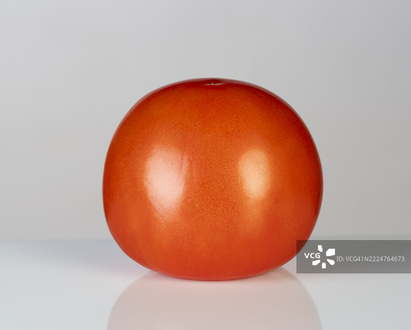 灰色背景上的整颗红番茄。图片素材
