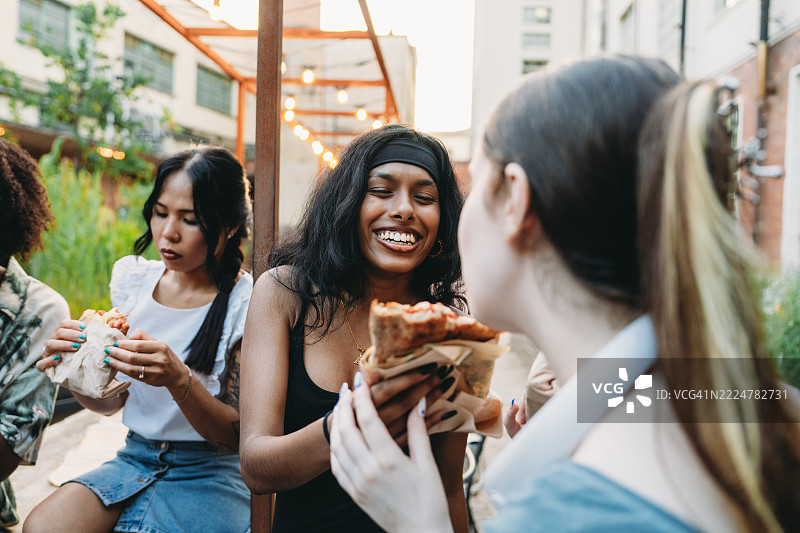 年轻女性在户外一起享受比萨和欢乐时光图片素材