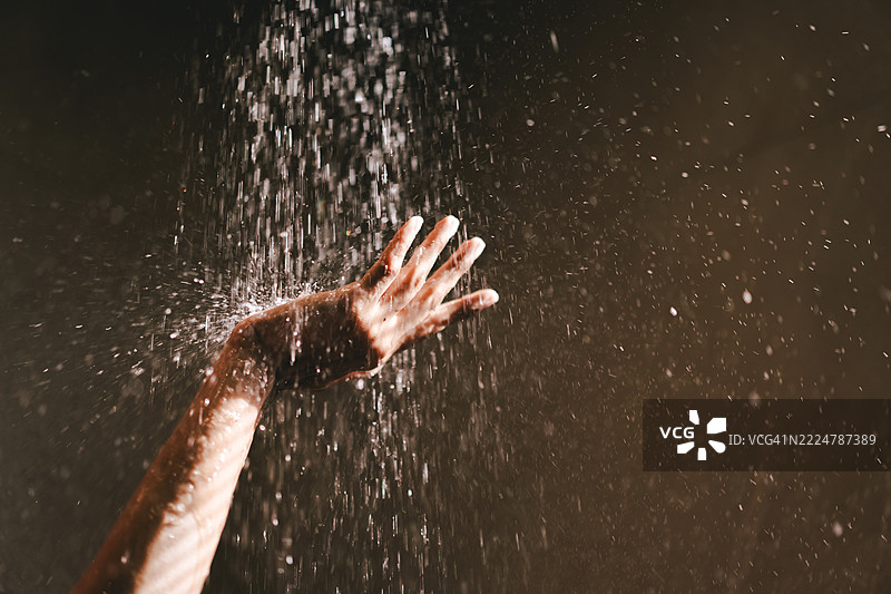 温柔的女性手在水滴中伸向淋浴喷头。夏季活动、个人卫生和对比淋浴的概念。图片素材