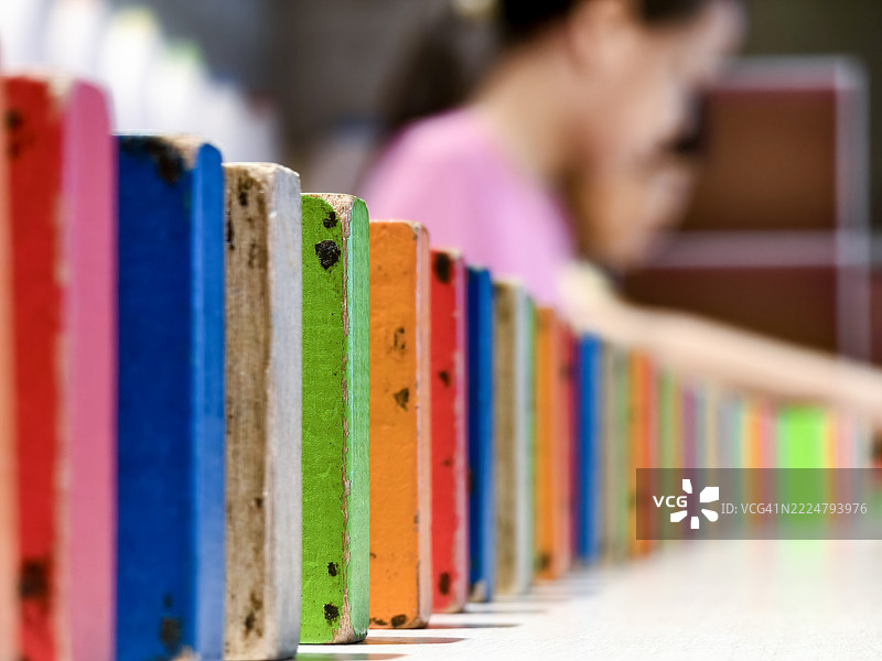 两个亚洲女孩正在玩多米诺骨牌。排列多米诺骨牌需要耐心，并能训练孩子们的专注力。图片素材