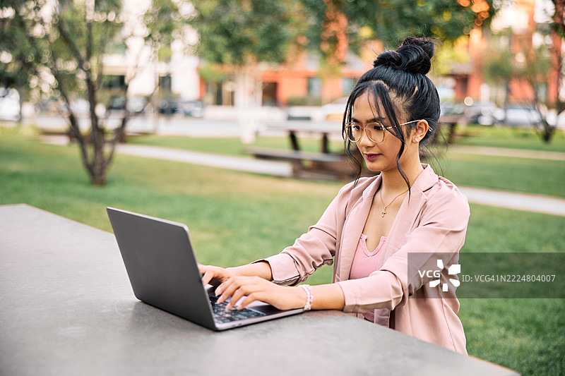 专注的亚洲女性自由职业者在户外工作图片素材