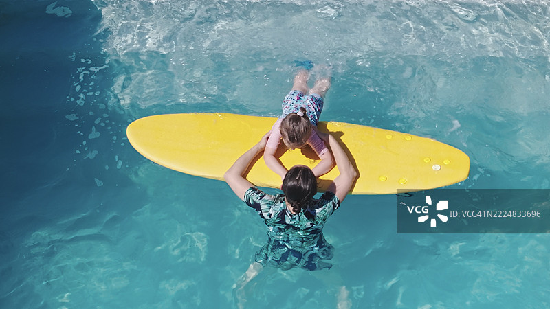 热带度假村中家庭在泳池的鸟瞰图。孩子学习游泳。图片素材