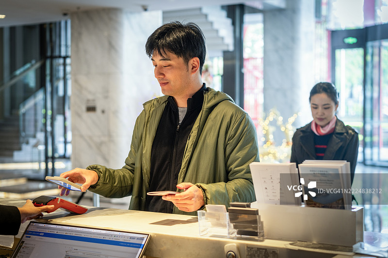 一位亚洲男子正在酒店办理入住。图片素材