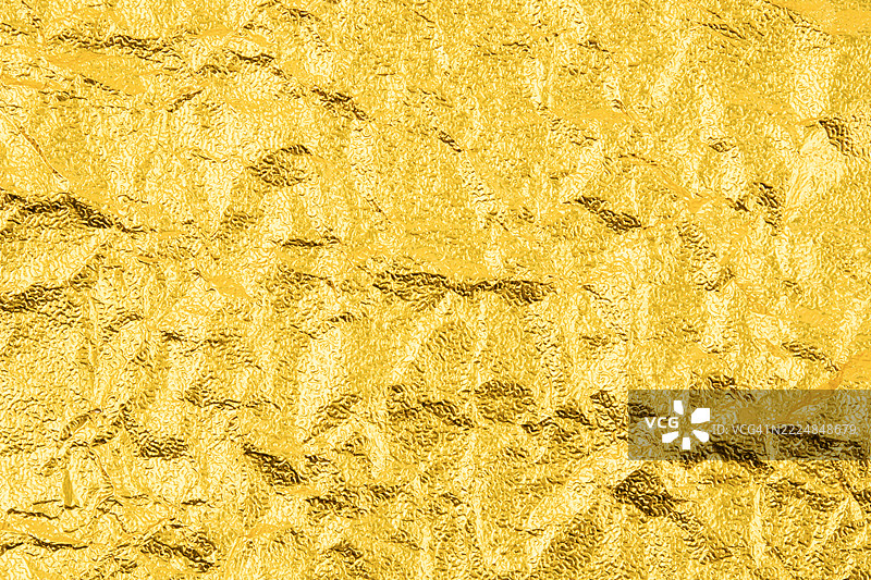 抽象的皱褶金属表面，带有金色反射。图片素材