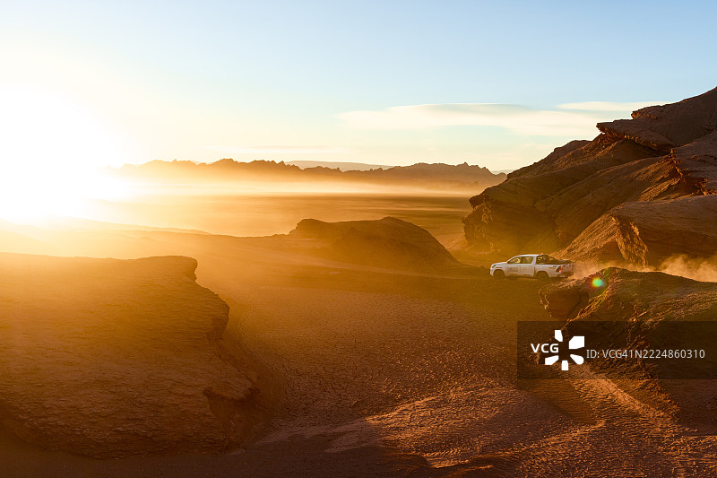 越野车在黎明时分的沙漠中行驶图片素材