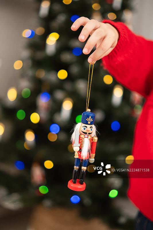 孩子在圣诞树前拿着坚果夹圣诞装饰品图片素材