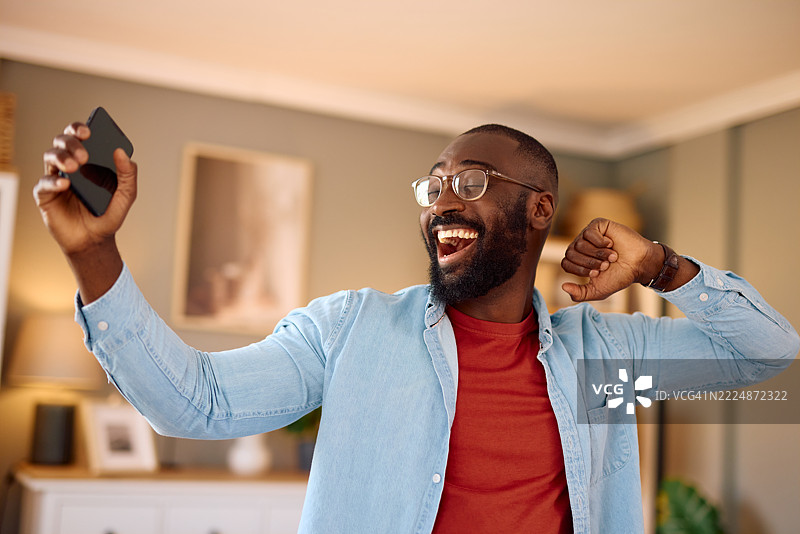 兴奋的男人在家中自拍并庆祝成功图片素材