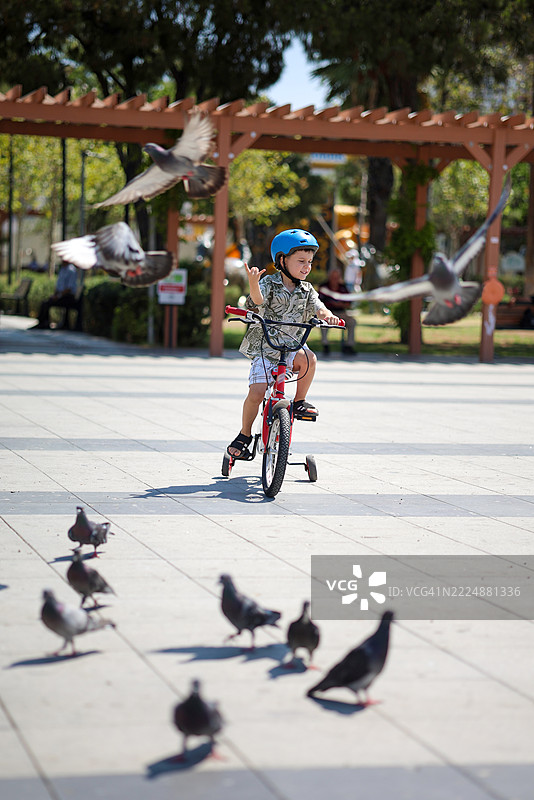 小男孩在公园骑着红色自行车图片素材