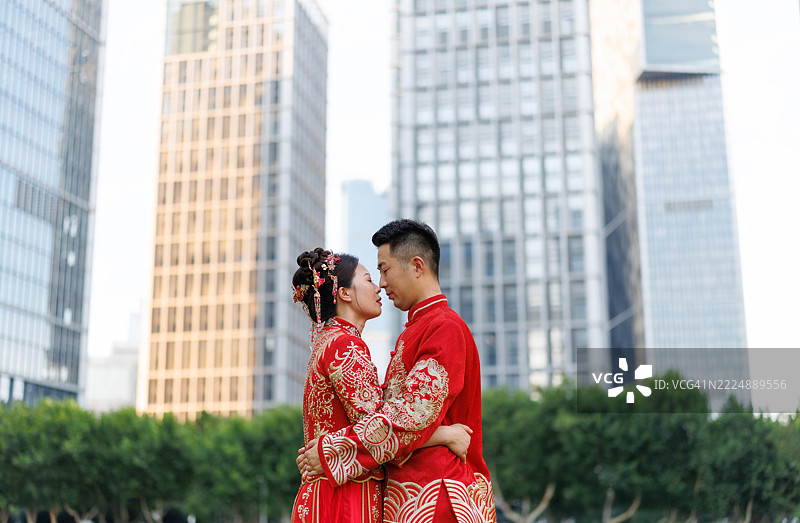 一对30多岁的中国新婚夫妇，身穿汉服，在现代城市中相拥庆祝他们的婚礼，传统服饰与现代城市的概念。图片素材