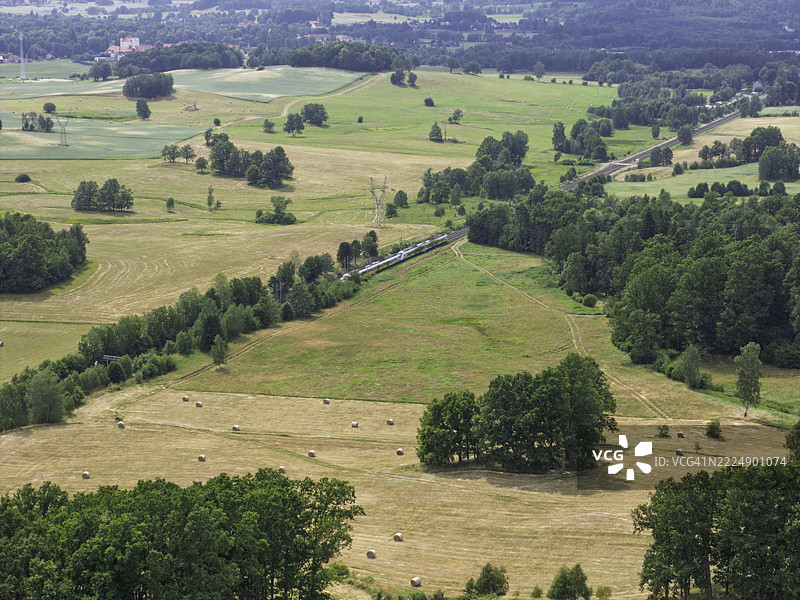 铁路穿过风景如画的乡村，绿意盎然的田野在小镇附近沐浴在正午的阳光下图片素材