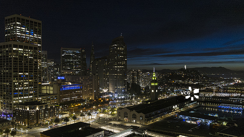 现代建筑在夜空中熠熠生辉。旧金山天际线与日落后灯光璀璨的渡轮大楼和海湾大桥。图片素材