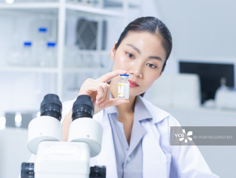 专业女性科学家，医学女性研究员在实验室中检查疫苗安瓿的测试。图片素材