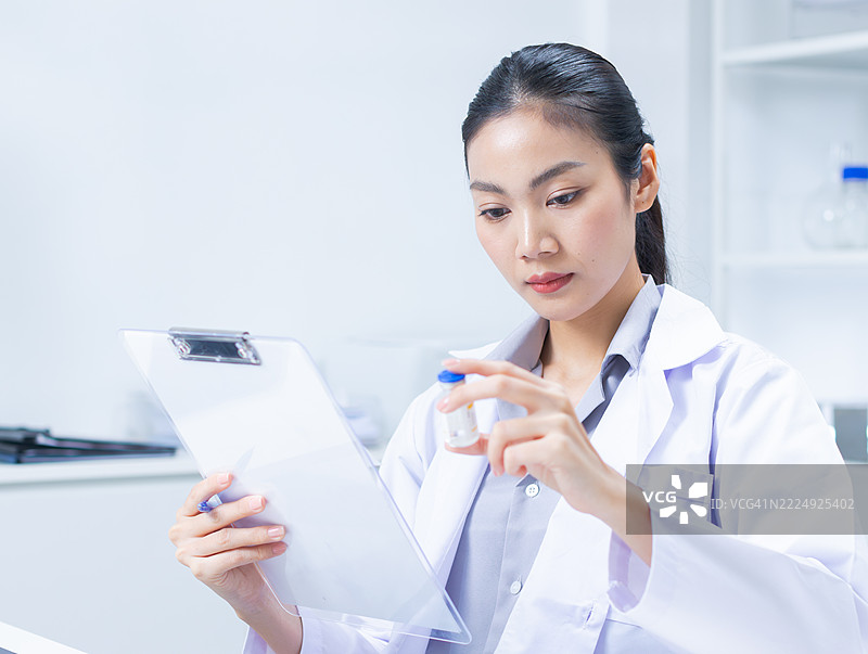 女性医学研究人员正在阅读和审查疫苗测试结果，致力于疫苗研究。图片素材