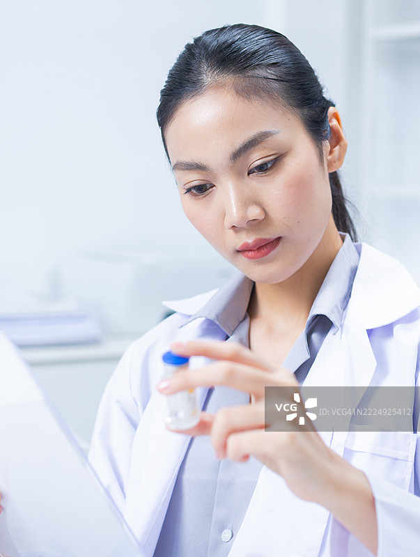 女性医学研究人员正在阅读和审查疫苗测试结果，致力于疫苗研究。图片素材