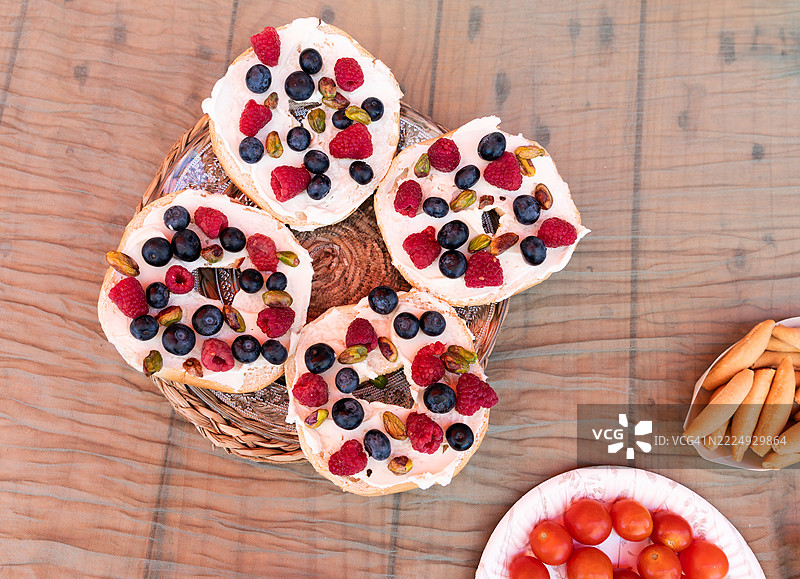 美味的贝果配奶油奶酪、蓝莓、覆盆子和开心果，摆放在木桌上图片素材