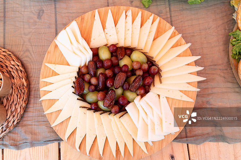 美味的奶酪拼盘，上面有葡萄和枣，摆放在木桌上图片素材